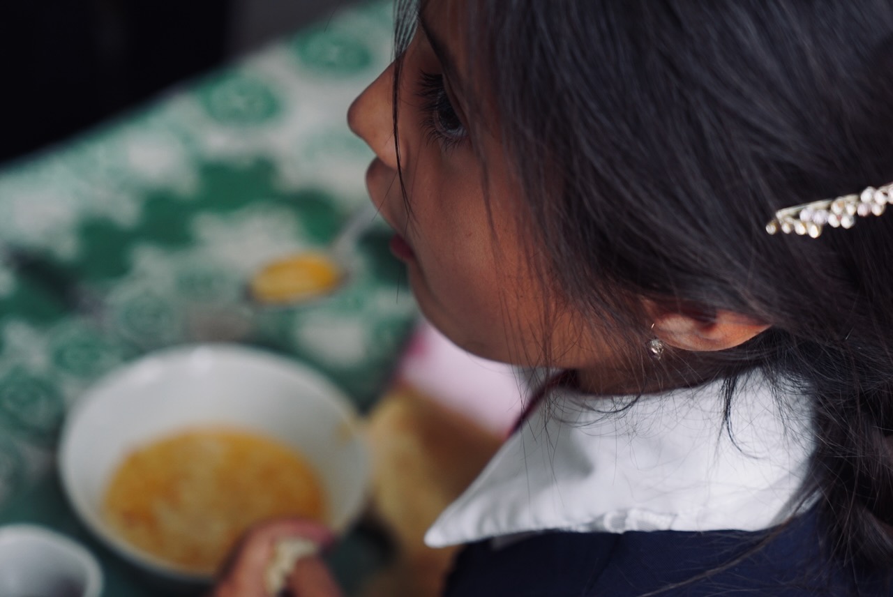 A schoolgirl in uniform eating from a bowl