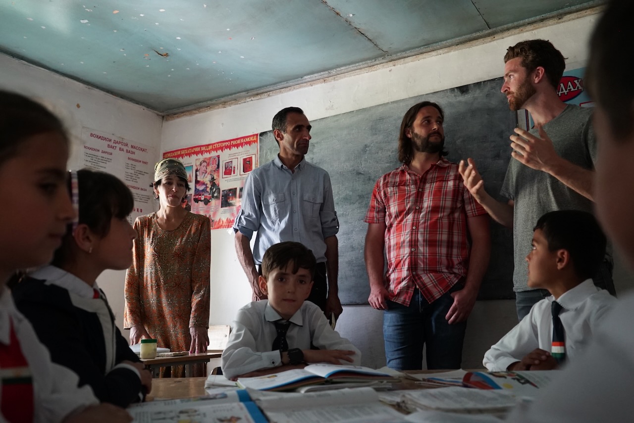 A classroom in rural Tajikistan, visitors standing with pupils at their desks