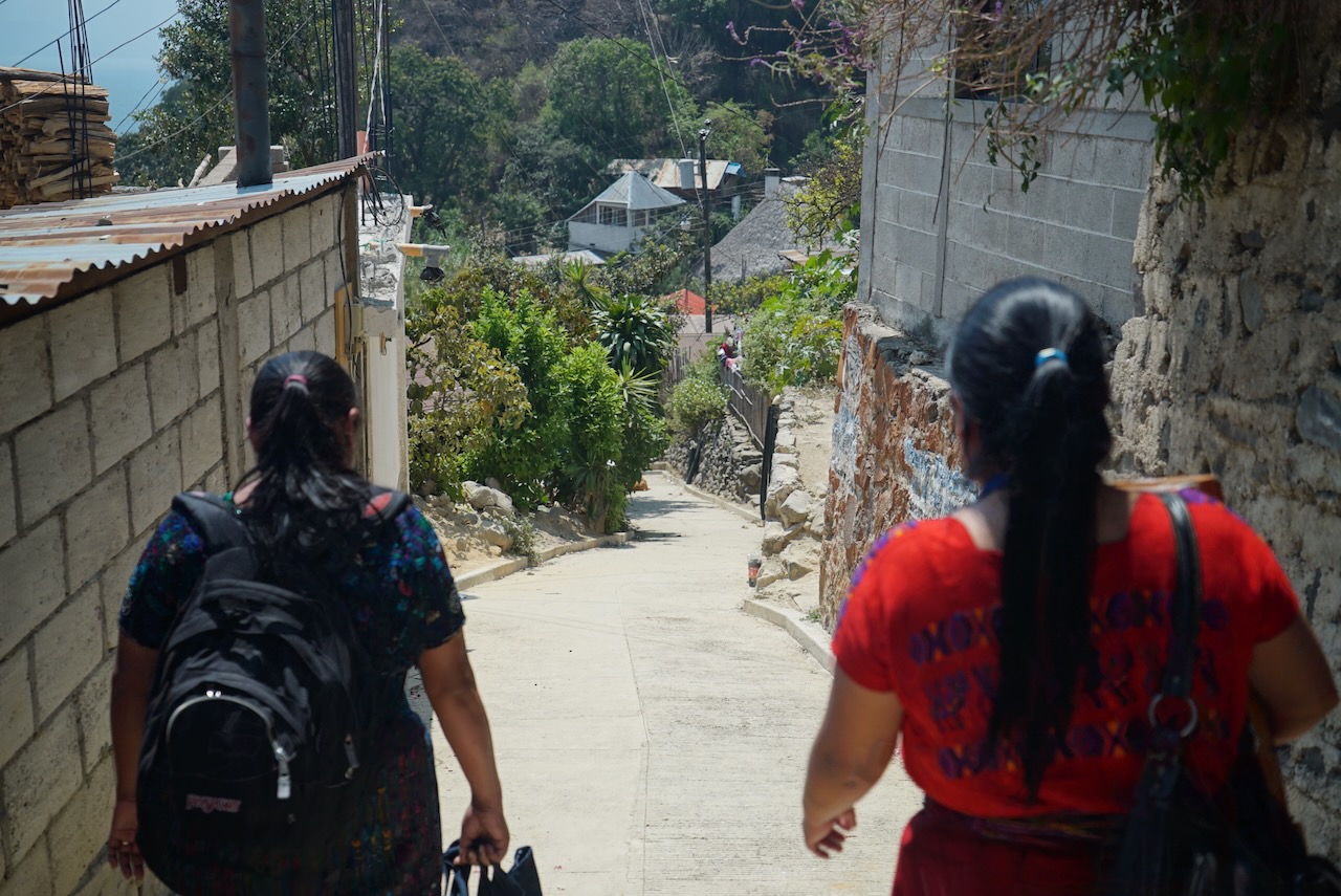 Two women walking down a steep lane between houses